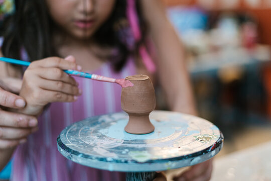 Unrecognizable girl painting on pottery