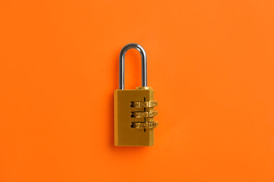 Modern combination lock on orange background, top view