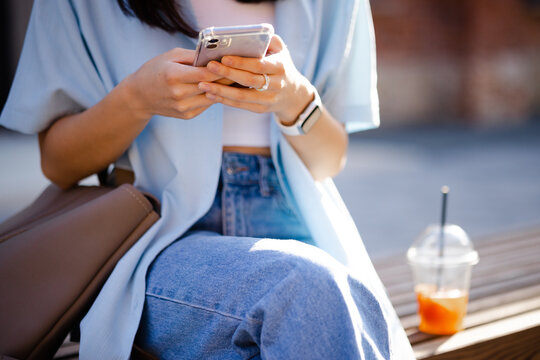 Girl with beverage using smartphone outdoor 
