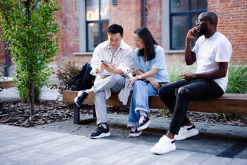 Friends resting on bench with their gadgets