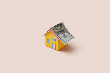 Yellow paper house with dollar banknote roof.