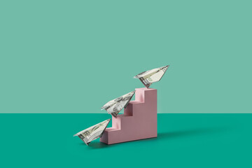 Dollar paper planes flying up from stairs.