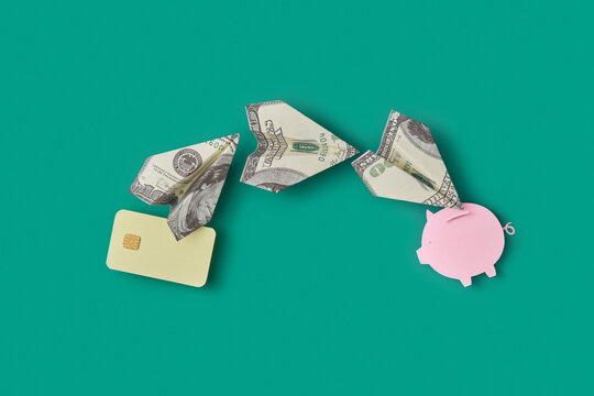 Dollar planes between card and piggy bank.