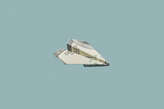Dollar banknote paper plane on gray background.