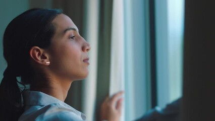 Young woman open curtain after a peaceful, relaxing sleep gets ready to go to work and lets the sun shine on her face. Happy to start her healthy morning skincare, beauty, make up and hair routine