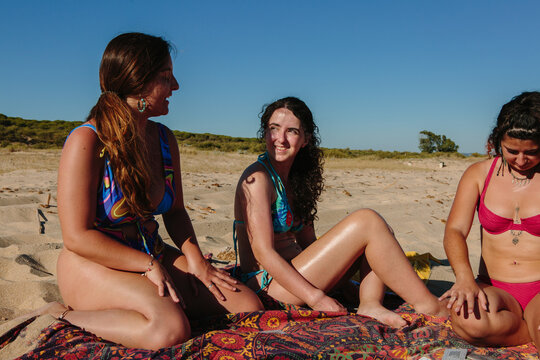 Three friends sitting on a beach chatting