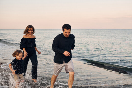 a young family runs along the seashore