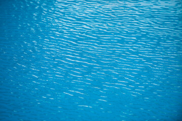 Fototapeta na wymiar Water background. Blue water, ripples and highlights. Texture of water surface and tiled bottom.