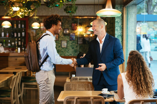 Multiracial businessmen shaking hands in restaurant