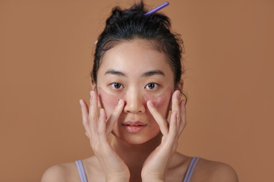 Asian girl with cosmetic collagen pink patches under eyes, cares