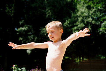 Little boy holding a stick while shirtless and in swimming trunks