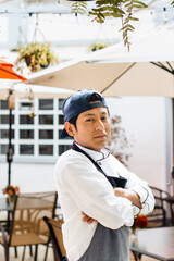 Portrait of a Hispanic chef looking at the camera and crossing his arms.