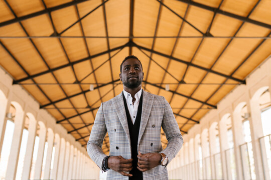 Cool confident black businessman adjusting suit in hall