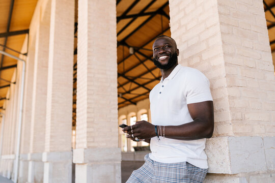 Cheerful black guy texting on smartphone and smiling