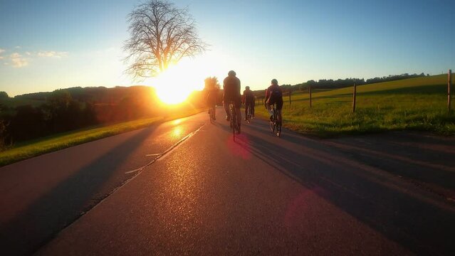 Cyclists cycling on mountain road in sunset lights