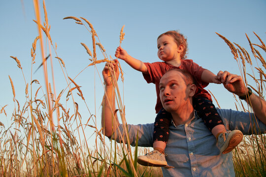 Young Dad Carrying Cute Son On His Shoulders