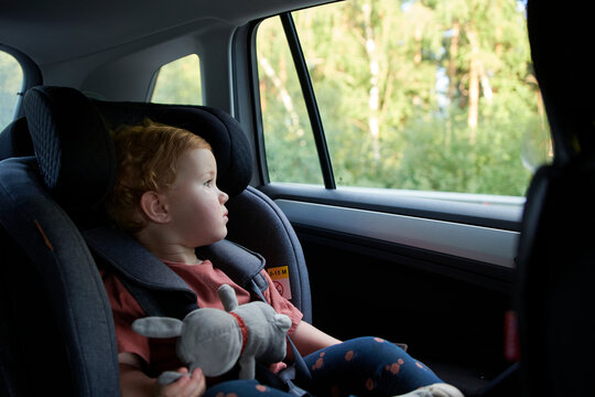 2 Year Old Girl In Car Safety Seat Looking Through The Window