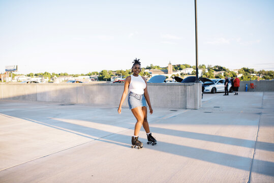 Young woman in roller skates on a rooftop at sunset