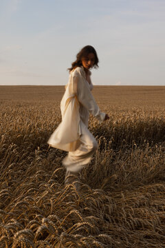 Woman in pyjamas moving through wheat 
