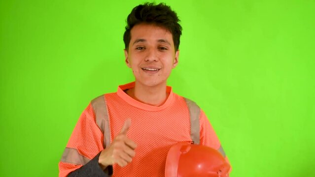 Joven hombre caucasico obrero en un fondo verde haciendo gestos de aprobaci&oacute;n 