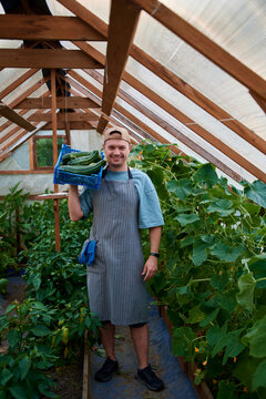 Full length portrait of a farmer with a basket of vegetables in a gree