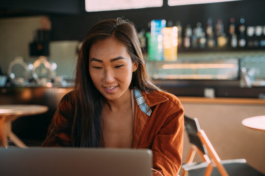 Asian woman using computer at cafe alone