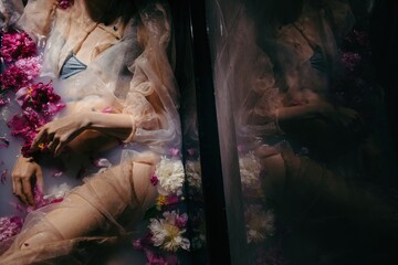 Anonymous woman in dark bath with flowers 