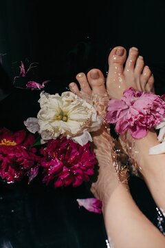Anonymous lady taking bath with fresh peonies
