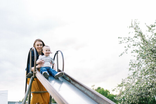 Mother and son playing outside on a slide in spring outdoors