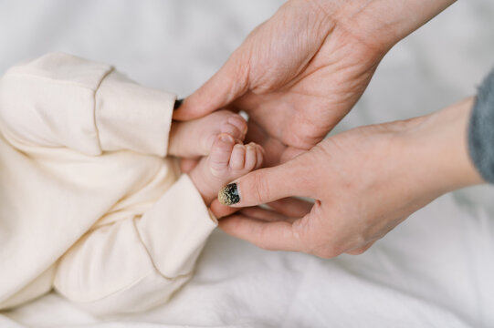 close up image of a mothers hands holding small newborn feet