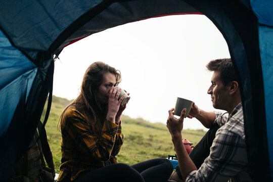 Couple drinking coffee camping in the woods