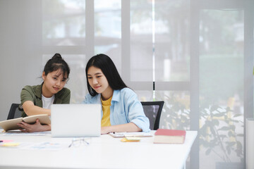 Young asian university students studying learning discuss working on computer.