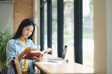 Young asian woman sitting and reading book.