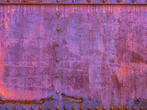 peeling blue, orange and purple paint over rusty metal