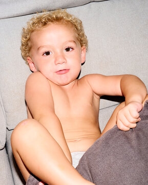 Toddler grabs pillow on sofa.