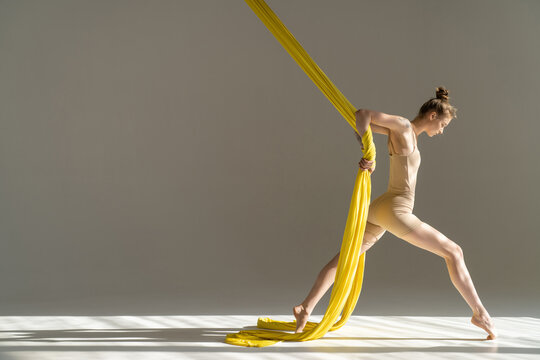 Circus artist with colorful fabric ribbons indoors