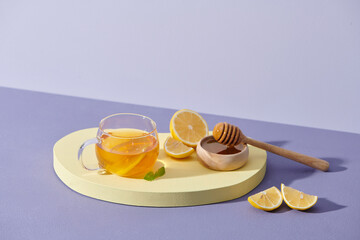 Tea with lemon and honey on the purple background.