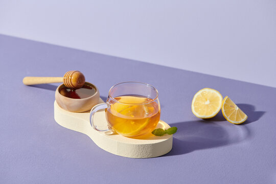 Tea with lemon and honey on the wooden tray on purple background.
