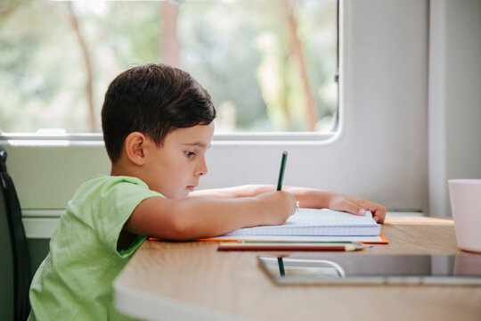 Little boy writing in notepad while working on project