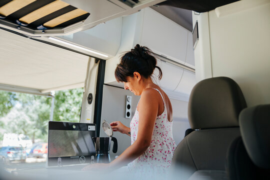 Woman preparing coffee inside a camper