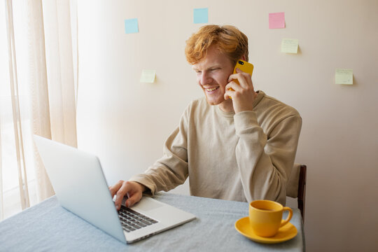 man talking on the phone and looking at his laptop
