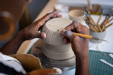 Closeup of a woman's hands working on pottery at her desk