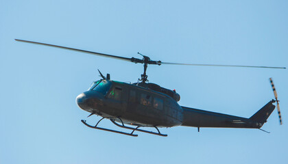 Fototapeta na wymiar Helicóptero estilo militar de color gris oscuro o negro con fondo de cielo azul