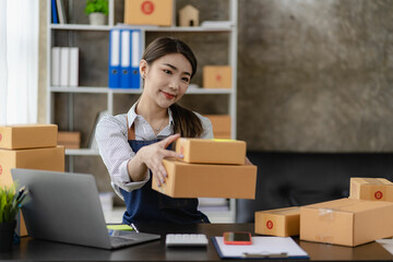 beautiful asian woman working at home selling online with yellow box and laptop on taking name orders from customers sme business concept parcel delivery