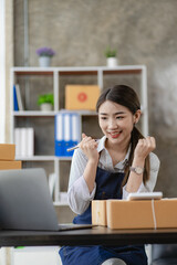 beautiful asian woman working at home selling online with yellow box and laptop on taking name orders from customers sme business concept parcel delivery