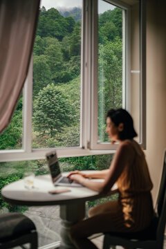 View from the window of the forest landscape with a girl with a laptop
