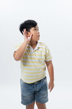 School child boy holds hand near ear.