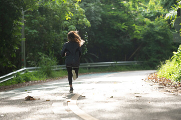 Young woman runner running on park road