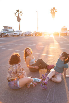 Gen Z friends sitting in a parking lot, laughing together at sunset