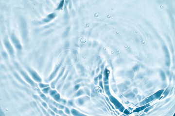 serum or cosmetic liquid drops falling on water wave surface abstract background for banner. Beauty...